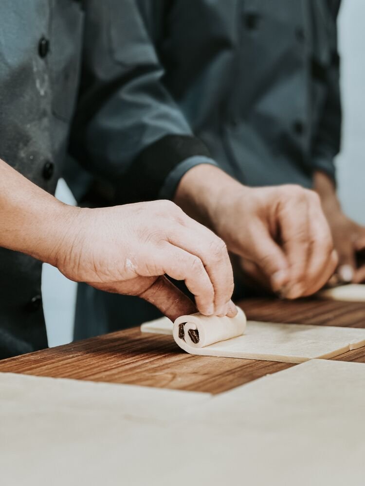 Baker hand-rolling pastry dough at Breadko
